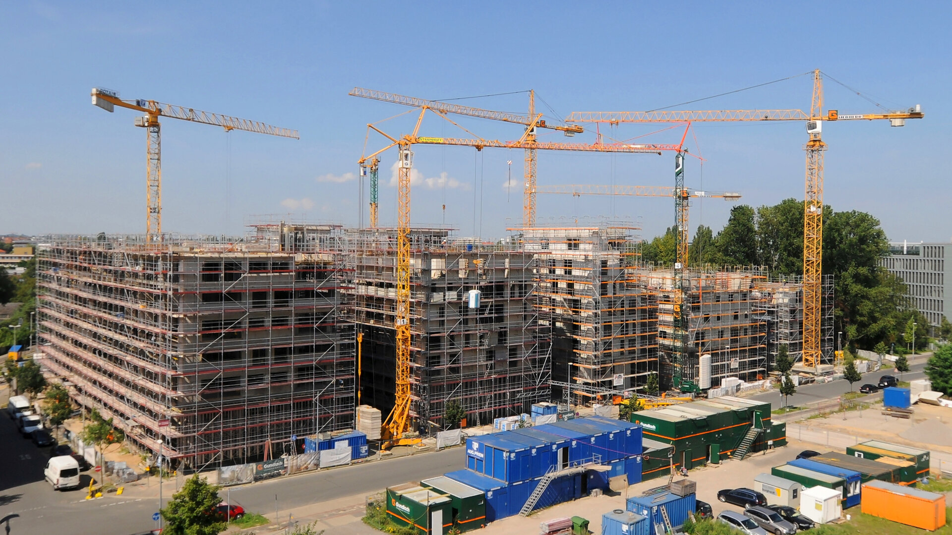 Baustelle des Gundlach Bauunternehmen. Auf dem Bild sind sechs Gundlach Krane vor einem gebauten Gebäude zu sehen.