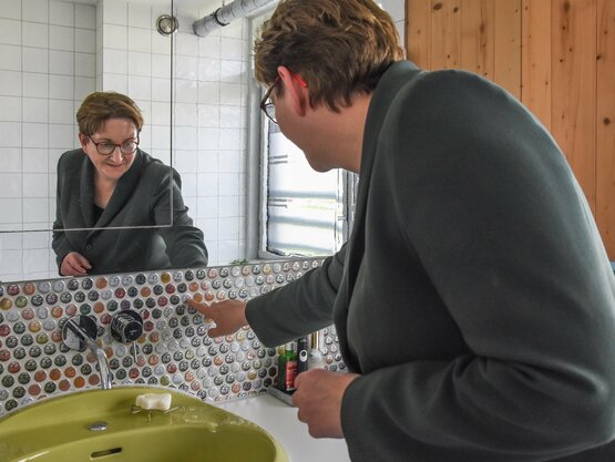 Bundesbauministerin Klara Geywitz schaut sich die Kronkorken-Sammlung im Bad an. 