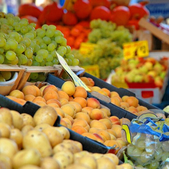 Dekoratives Bild von einem Gemüstestand. Immer freitags findet im Pelikan-Viertel der Wochenmarkt statt.