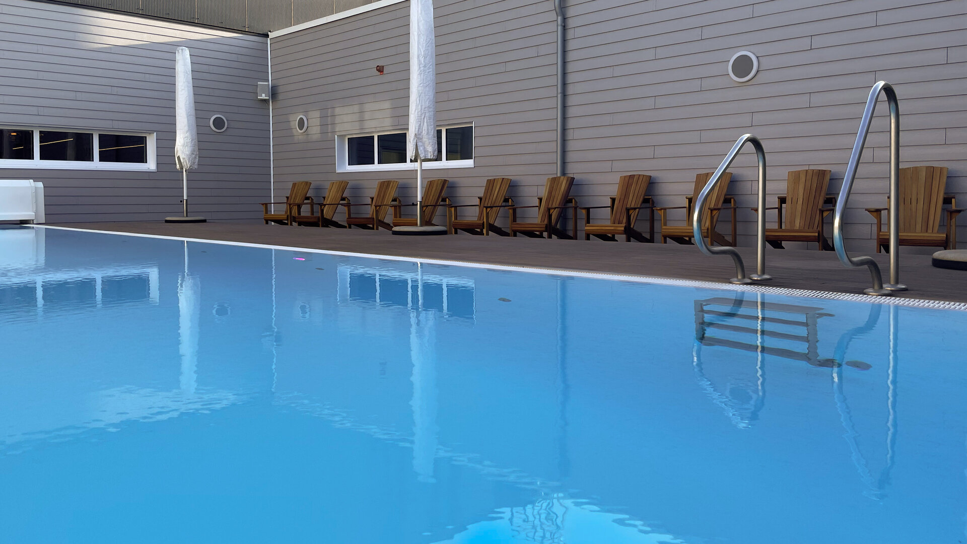 Innenliegender Pool mit Sonnenschirmen und Holzliegen