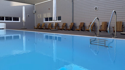 Innenliegender Pool mit Sonnenschirmen und Holzliegen