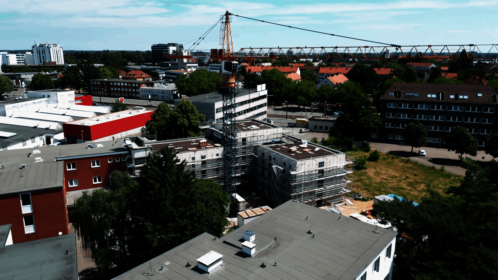 Luftaufnahme eines modernen Gebäudekomplexes mit zwei rechteckigen Flachdachbauten, die sich im Bau befinden. Die Fassaden sind eingerüstet, Baumaterialien und Baucontainer stehen auf dem Gelände. Im Kontext handelt es sich um Micro Apartments für ehemals wohnungslose Menschen in der Büttnerstraße, die durch das Generalunternehmen Gundlach erbaut wurden.