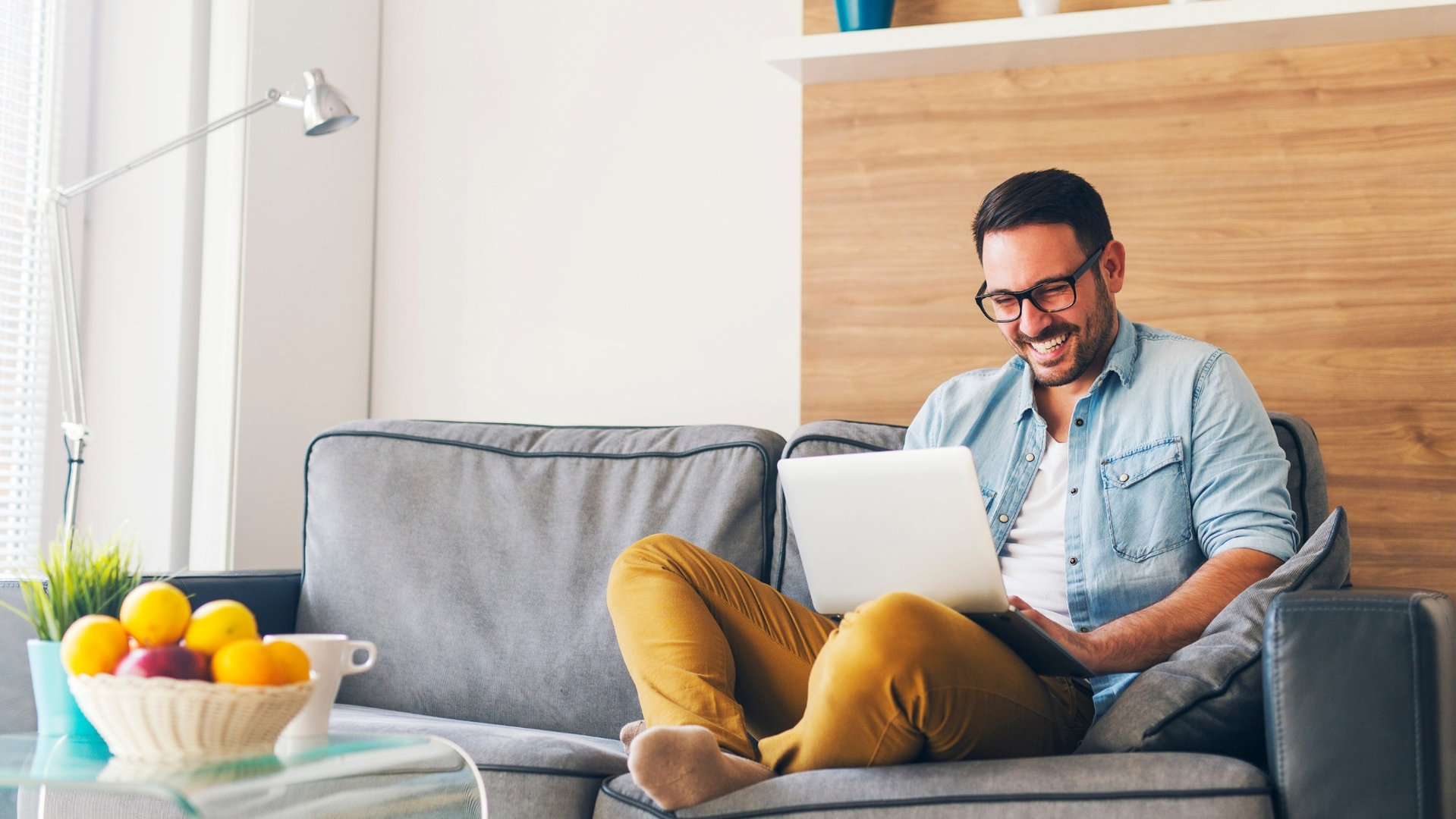 Mann auf Sofa mit Laptop. Entspannt, dank des digitalen Services der Gundlach Immobilienverwaltung Hannover